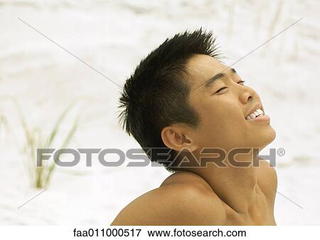 Young man on beach with head back and eyes closed View Large Photo Image Stock Photo - Young man on beach with head back and eyes closed. Fotosearch