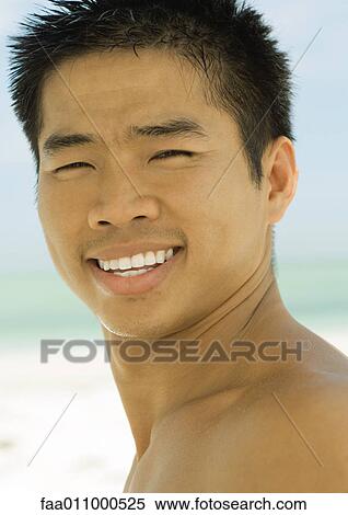 Young man smiling, beach in background, portrait View Large Photo Image Stock Photography - Young man smiling, beach in background, portrait. Fotosearch