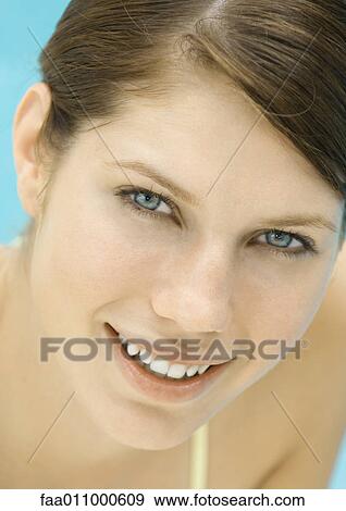 Stock Photo - Young woman by pool, smiling, portrait. Fotosearch
