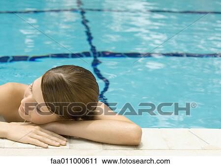 Stock Image - Young woman resting head on side of pool. Fotosearch