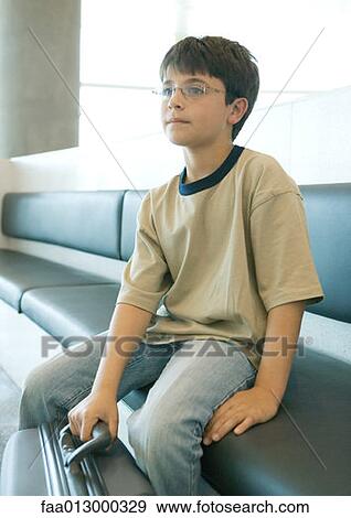 Stock Photo - Boy sitting on bench with suitcase. Fotosearch