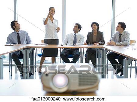 Stock Image - Business colleagues having meeting, videoprojector in foreground. Fotosearch