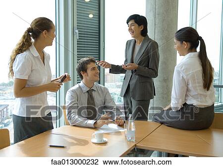Business colleagues standing at sitting at table, discussing View Large Photo Image Stock Image - Business colleagues standing at sitting at table, discussing . Fotosearch