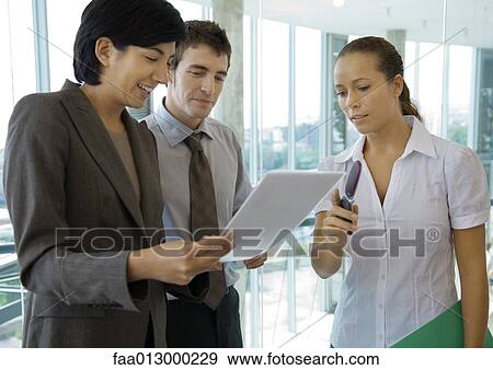 Business colleagues standing, discussing document View Large Photo Image Stock Photo - Business colleagues standing, discussing document. Fotosearch