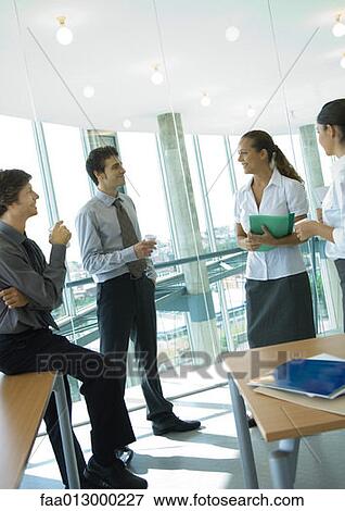 Stock Photo - Business colleagues standing with cups of coffee, chatting. Fotosearch