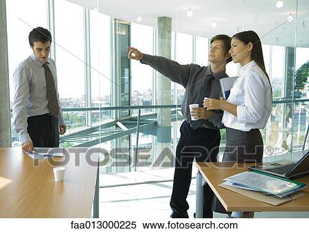 Stock Photography - Business colleagues standing with cups of coffee, chatting. Fotosearch