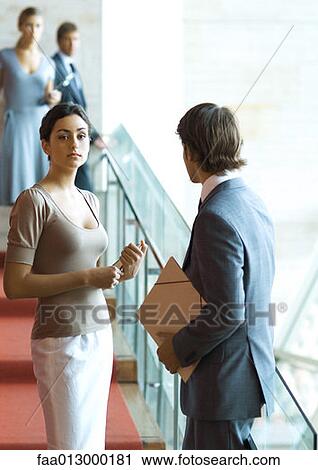 Stock Image - Businessman and woman talking on stairs. Fotosearch