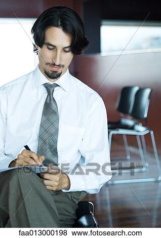 Businessman taking notes on crossed legs View Large Photo Image Stock Photo - Businessman taking notes on crossed legs. Fotosearch