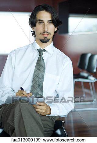 Businessman taking notes on crossed legs View Large Photo Image Stock Photo - Businessman taking notes on crossed legs. Fotosearch