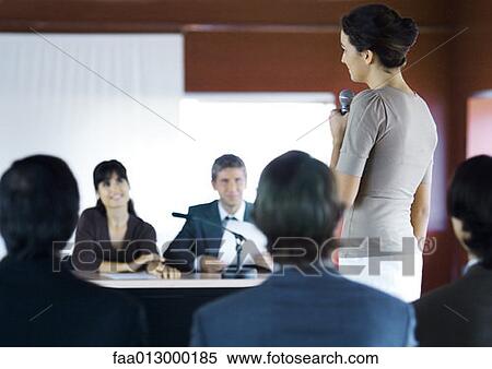 Stock Photography - Businesspeople in seminar, one woman standing with microphone. Fotosearch