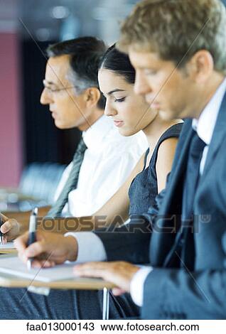 Stock Image - Businesspeople sitting, taking notes. Fotosearch