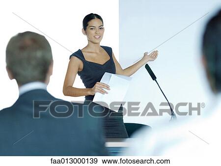 Stock Photo - Businesswoman speaking with microphone during seminar. Fotosearch