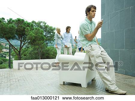 Casually dressed young executives working outdoors, man in foreground checking cell phone messages View Large Photo Image Stock Image - Casually dressed young executives working outdoors, man in foreground checking cell phone messages. Fotosearch