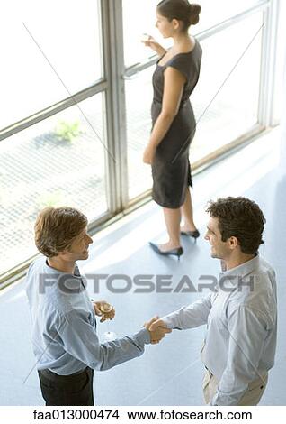 Picture - Executives shaking hands during cocktail party. Fotosearch