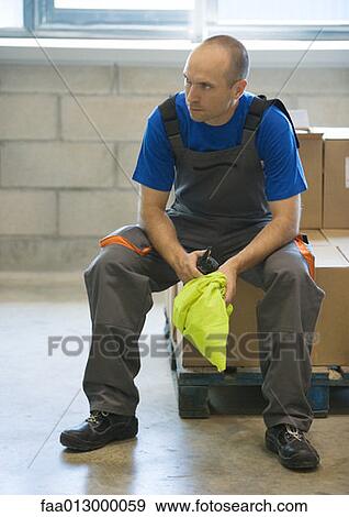 Stock Photo - Factory worker sitting on cardboard box. Fotosearch