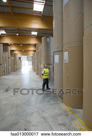 Factory worker standing next to rolls of paper View Large Photo Image Stock Photo - Factory worker standing next to rolls of paper. Fotosearch
