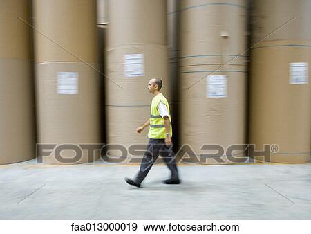 Factory worker walking past rolls of paper View Large Photo Image Stock Photo - Factory worker walking past rolls of paper. Fotosearch
