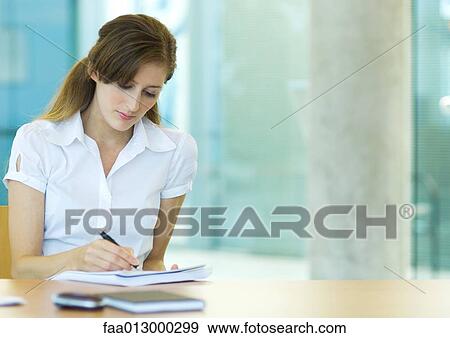 Female office worker sitting at desk, working View Large Photo Image Stock Photo - Female office worker sitting at desk, working. Fotosearch