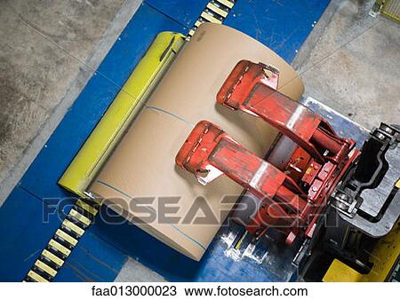 Stock Image - Fork lift picking up roll of paper. Fotosearch