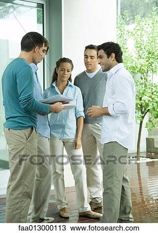 Group of casually dressed adults, standing together, discussing documents View Large Photo Image Stock Image - Group of casually dressed adults, standing together, discussing documents. Fotosearch