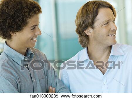 Stock Photography - Male executive and office worker smiling, looking out of frame. Fotosearch