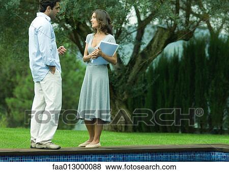 Stock Photo - Man and woman talking by side of pool. Fotosearch