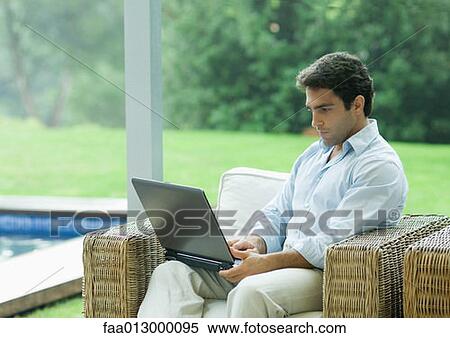 Man using laptop outdoors in armchair View Large Photo Image Stock Photography - Man using laptop outdoors in armchair. Fotosearch