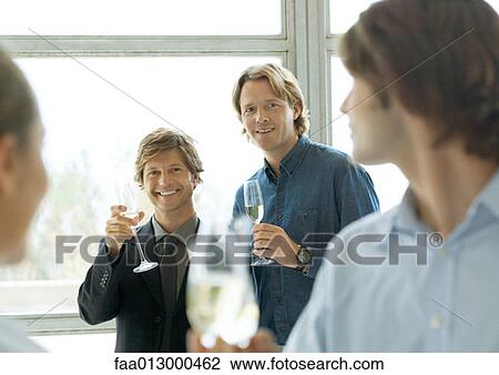 Men holding up glasses of champagne during cocktail party View Large Photo Image Stock Image - Men holding up glasses of champagne during cocktail party. Fotosearch