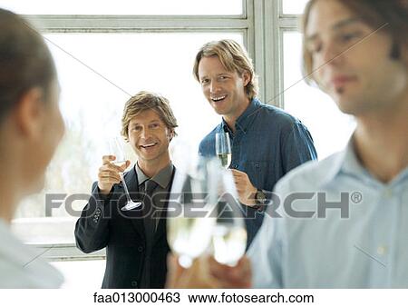 Men holding up glasses of champagne during cocktail party View Large Photo Image Stock Image - Men holding up glasses of champagne during cocktail party. Fotosearch