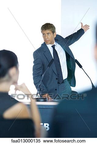 Stock Photography - Speaker standing next to microphones during seminar. Fotosearch