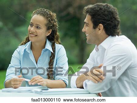 Woman and man, outdoors, sitting with documents and pen at table View Large Photo Image Stock Image - Woman and man, outdoors, sitting with documents and pen at table. Fotosearch