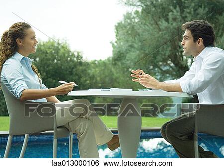 Woman and man sitting outdoors by pool, working View Large Photo Image Stock Photograph - Woman and man sitting outdoors by pool, working. Fotosearch