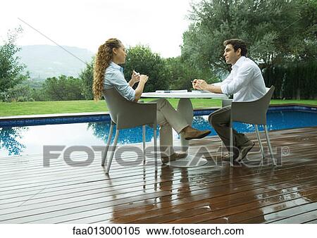 Woman and man sitting outdoors by pool, working View Large Photo Image Stock Photography - Woman and man sitting outdoors by pool, working. Fotosearch
