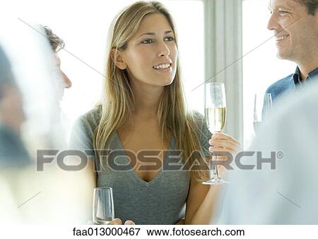 Woman holding glass of champagne during cocktail party View Large Photo Image Stock Photo - Woman holding glass of champagne during cocktail party. Fotosearch
