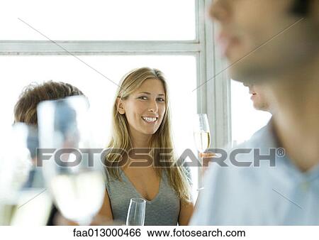 Stock Photograph - Woman holding glass of champagne during cocktail party. Fotosearch