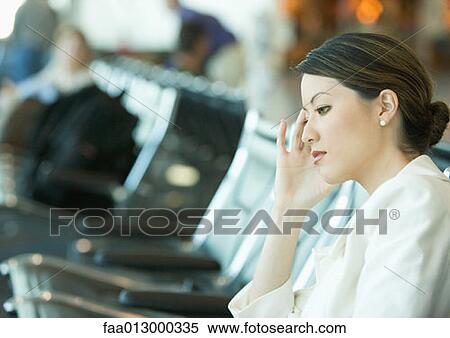 Woman sitting in airport lounge, holding head View Large Photo Image Stock Photography - Woman sitting in airport lounge, holding head. Fotosearch