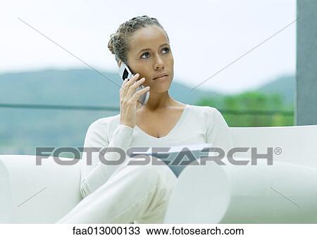 Woman sitting outdoors in armchair, using cell phone and holding document View Large Photo Image Stock Image - Woman sitting outdoors in armchair, using cell phone and holding document. Fotosearch