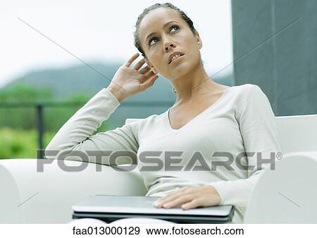 Woman sitting outdoors in armchair, with laptop closed on lap View Large Photo Image Stock Photo - Woman sitting outdoors in armchair, with laptop closed on lap. Fotosearch