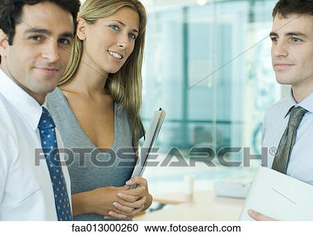 Stock Image - Young executives, one smiling at camera. Fotosearch