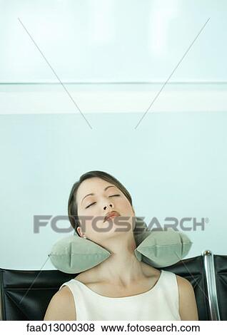 Stock Photo - Young woman sleeping in airport lounge, using neck pillow. Fotosearch