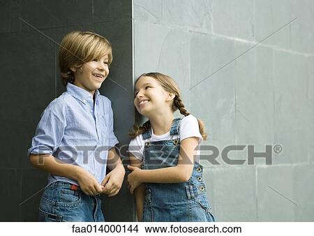 Boy and girl, leaning against corner of wall, laughing View Large Photo Image Picture - Boy and girl, leaning against corner of wall, laughing. Fotosearch