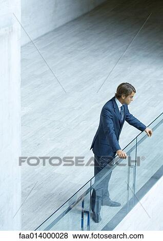 Businessman looking over guard rail, high angle view View Large Photo Image Stock Photo - Businessman looking over guard rail, high angle view. Fotosearch