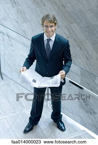 Stock Image - Businessman reading newspaper, portrait, high angle view. Fotosearch