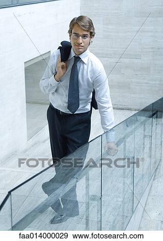 Stock Photo - Businessman standing holding jacket over shoulder, full length portrait. Fotosearch
