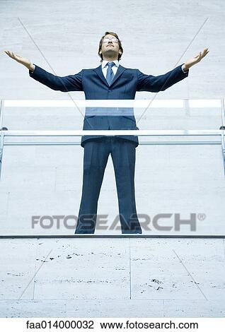 Businessman standing with arms raised, portrait, low angle view View Large Photo Image Stock Image - Businessman standing with arms raised, portrait, low angle view. Fotosearch