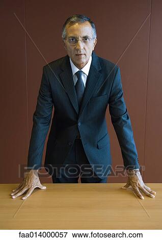 Businessman standing with hands on table, portrait View Large Photo Image Stock Photo - Businessman standing with hands on table, portrait. Fotosearch