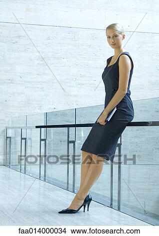 Businesswoman leaning against guard rail, full length portrait View Large Photo Image Picture - Businesswoman leaning against guard rail, full length portrait. Fotosearch