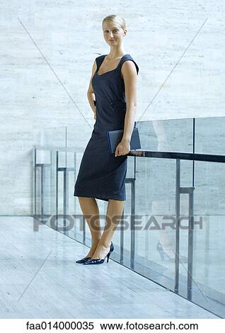 Businesswoman leaning against guard rail, full length portrait View Large Photo Image Stock Photography - Businesswoman leaning against guard rail, full length portrait. Fotosearch