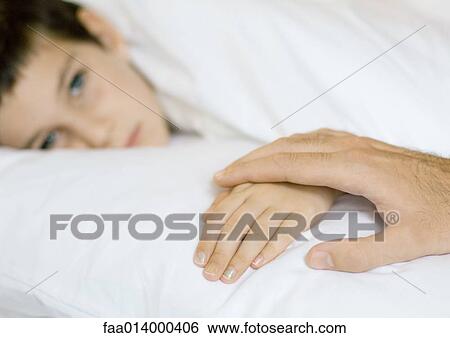 Child lying in bed, father's hand on child's View Large Photo Image Stock Photograph - Child lying in bed, father's hand on child's. Fotosearch