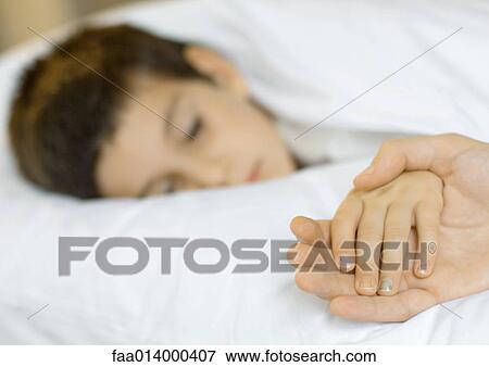 Stock Photo - Child lying in bed, father's hand holding child's. Fotosearch